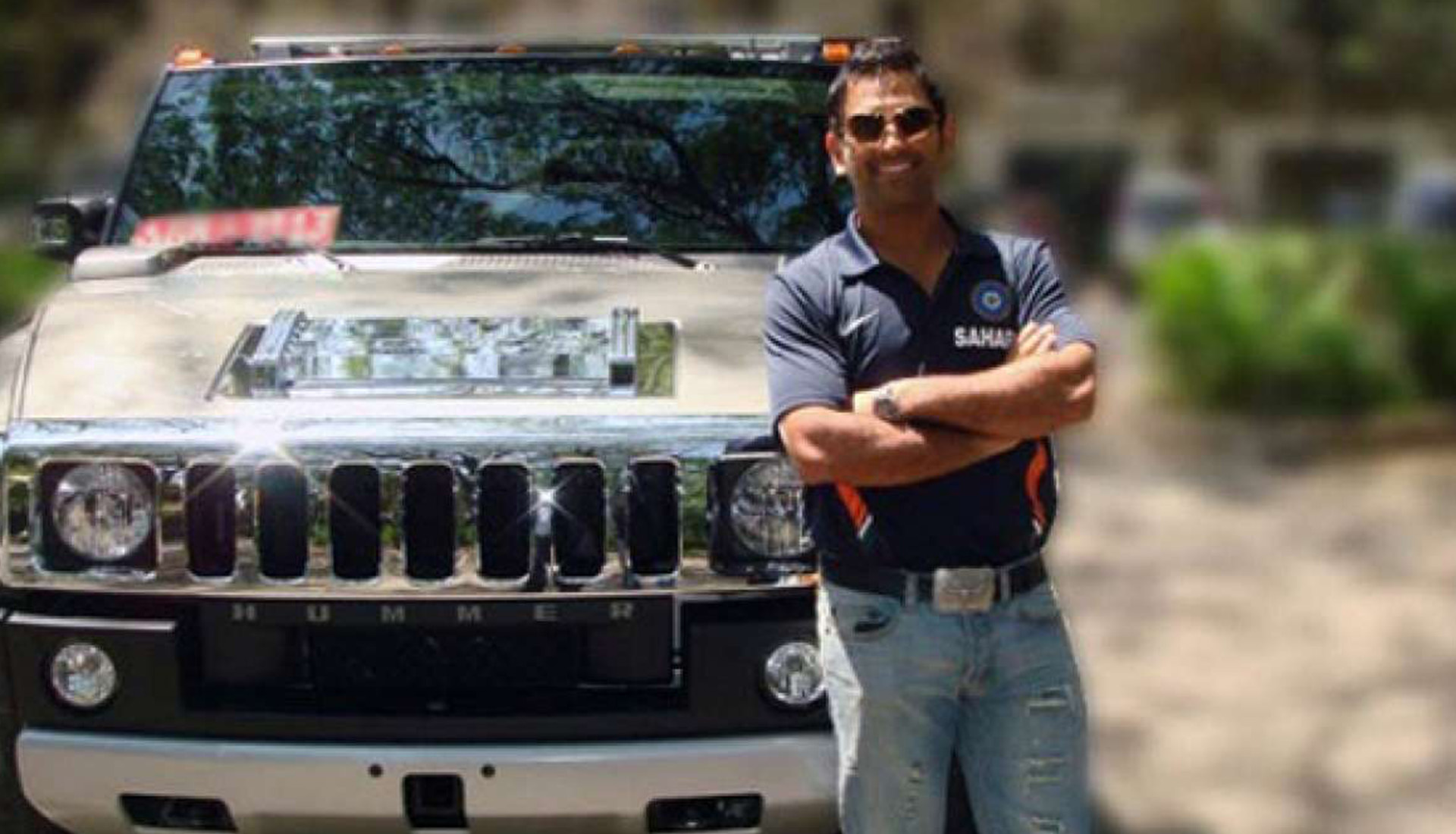 Man in sports jersey standing by white Hummer outdoors.