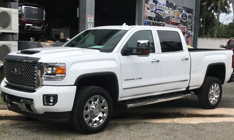 White GMC Denali HD truck parked outside auto shop.