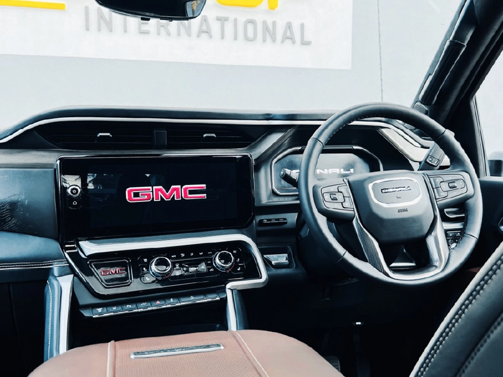 GMC vehicle interior with steering wheel and dashboard display.