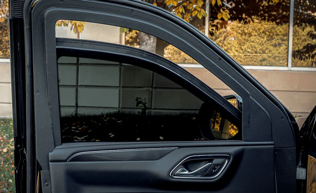 Car door open, revealing autumn trees reflection.