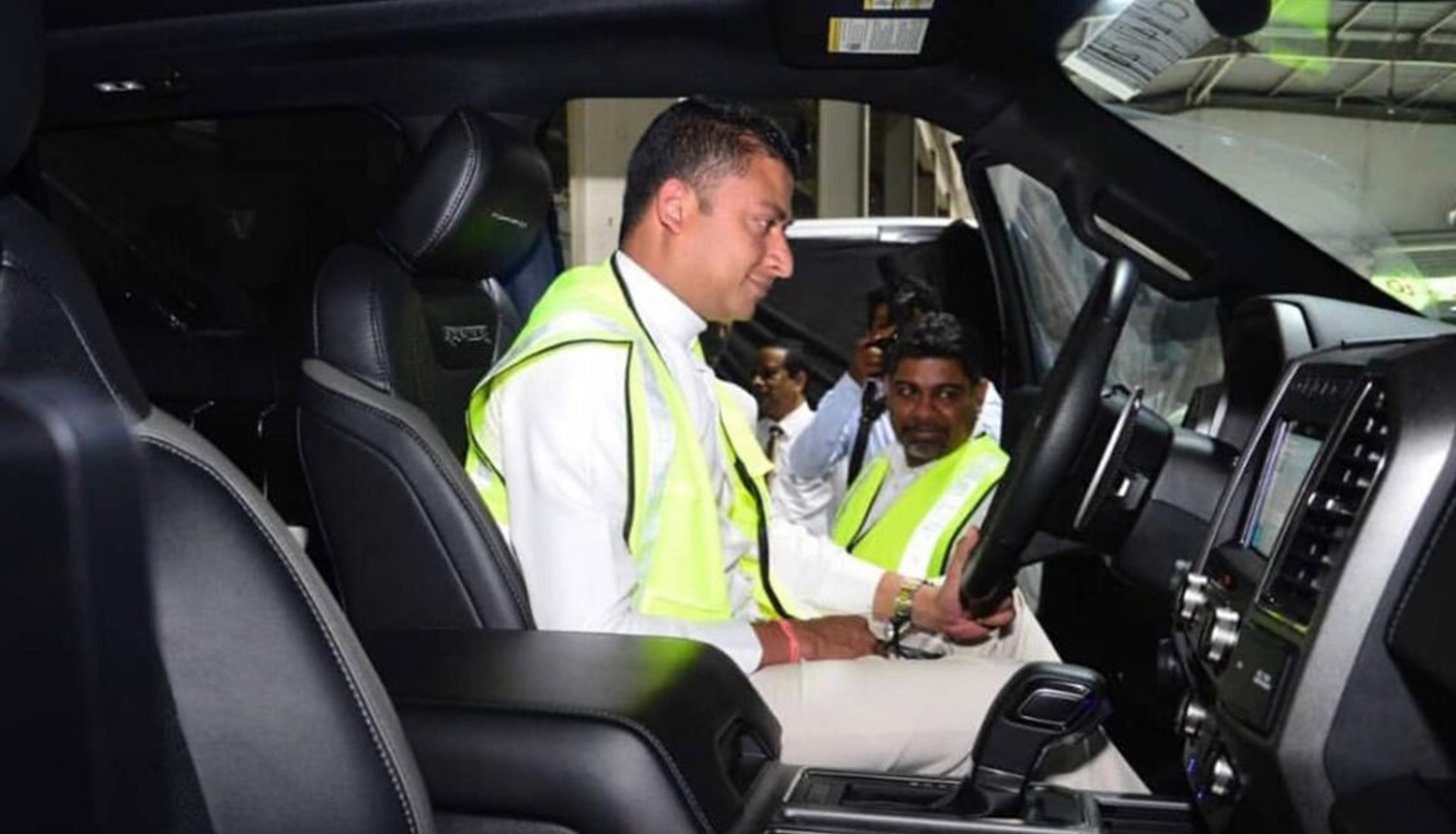 Men in high-visibility vests inspecting luxury vehicle interior.