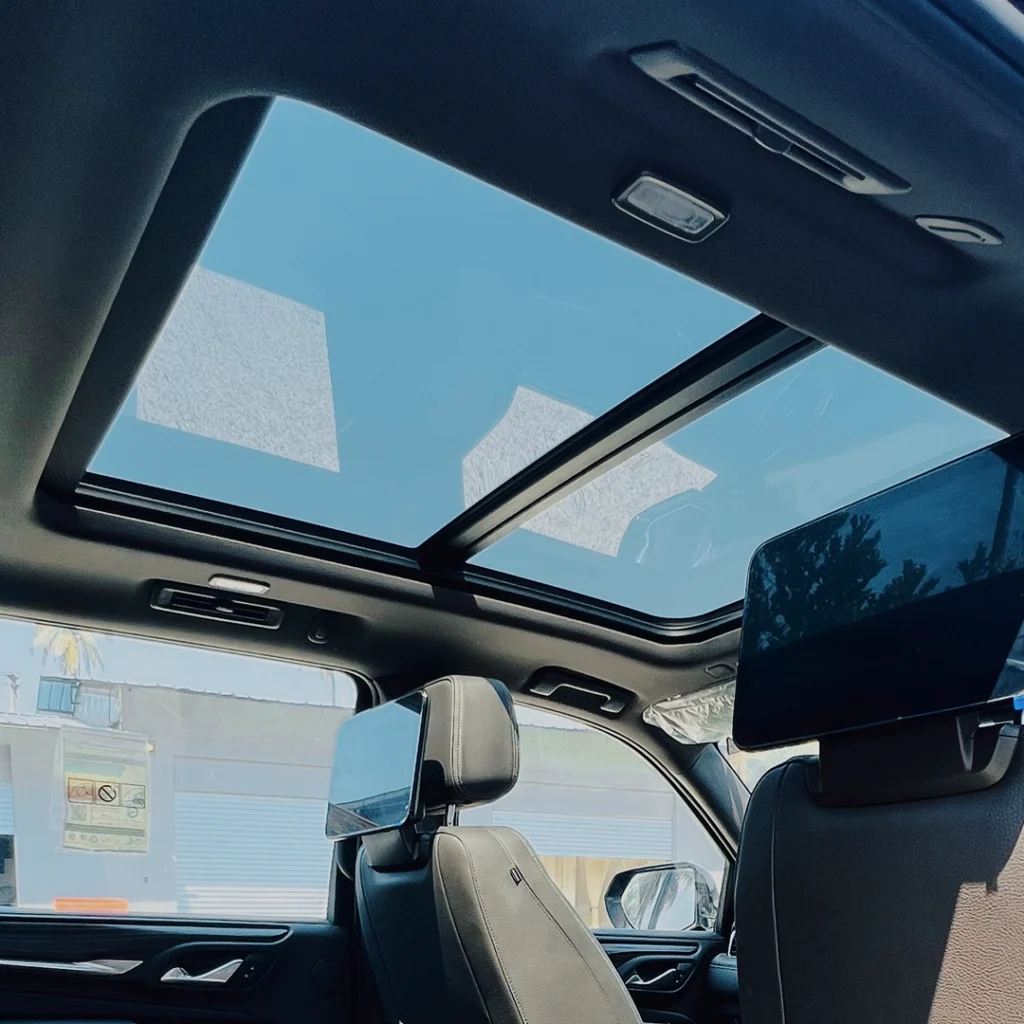 Car interior with open sunroof and rearview mirror visible.