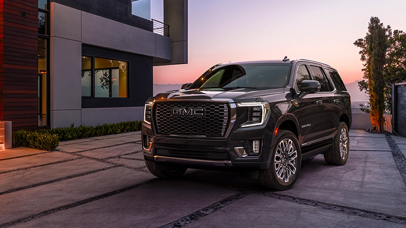 2024 gmc yukon denali in right-hand drive-by-autogroup-international parked in driveway during a sunset