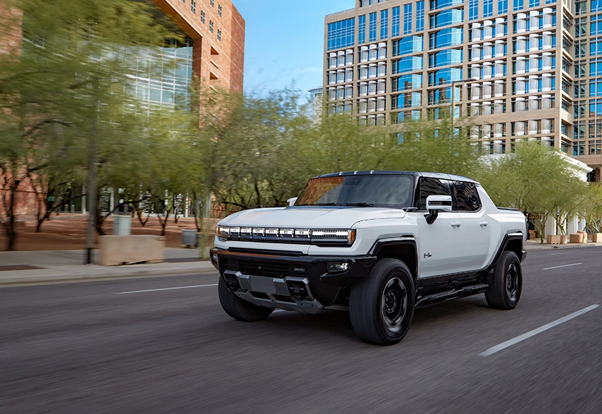 White electric pickup truck driving through urban street