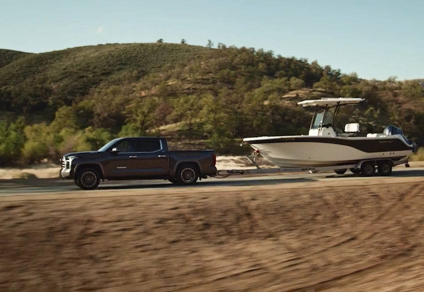 toyota tundra towing a boat at speed along a road