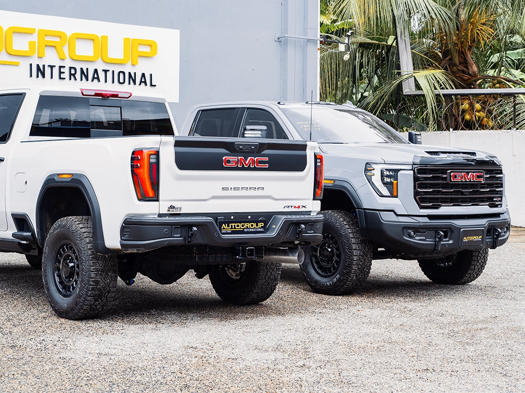 a white and grey 2024 GMC Sierra 2500HD AT4X in Right hand Drive parked next to each other back to front