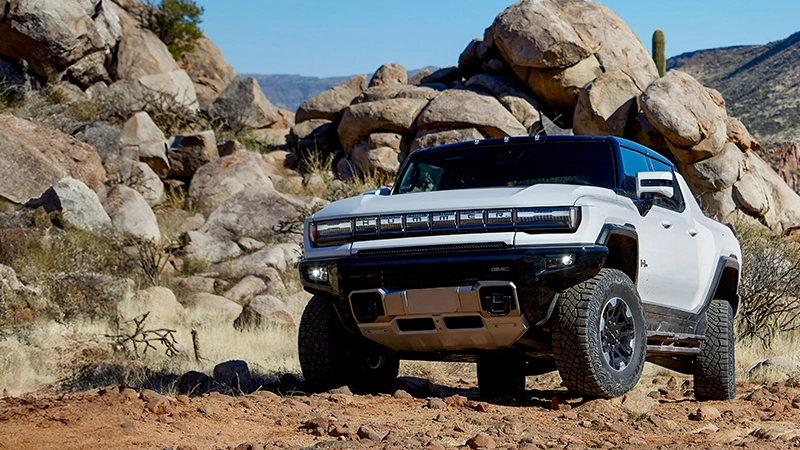 White Hummer EV pickup truck navigating rocky desert terrain