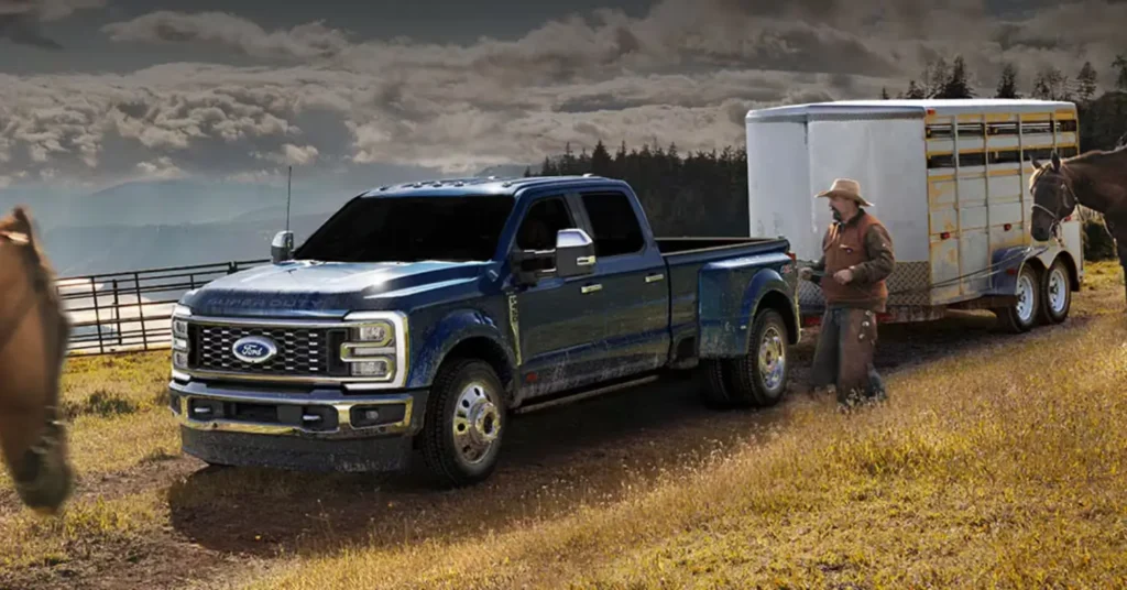 Man with horse beside Ford truck towing trailer.