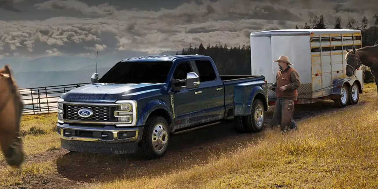 Man with horse beside Ford truck towing trailer.