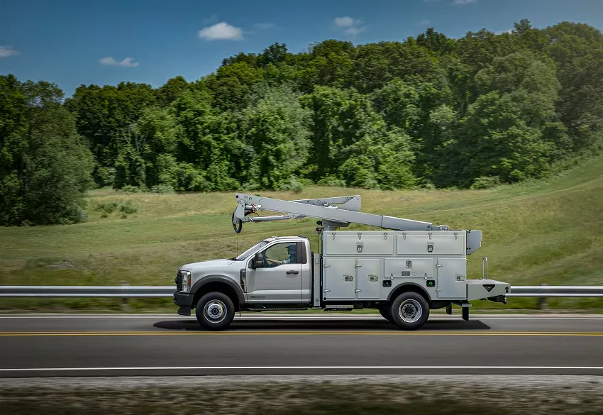 2026 Ford F 550 utility truck driving on highway near trees