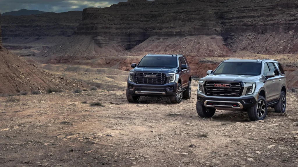 Two GMC SUVs parked in rocky desert landscape.