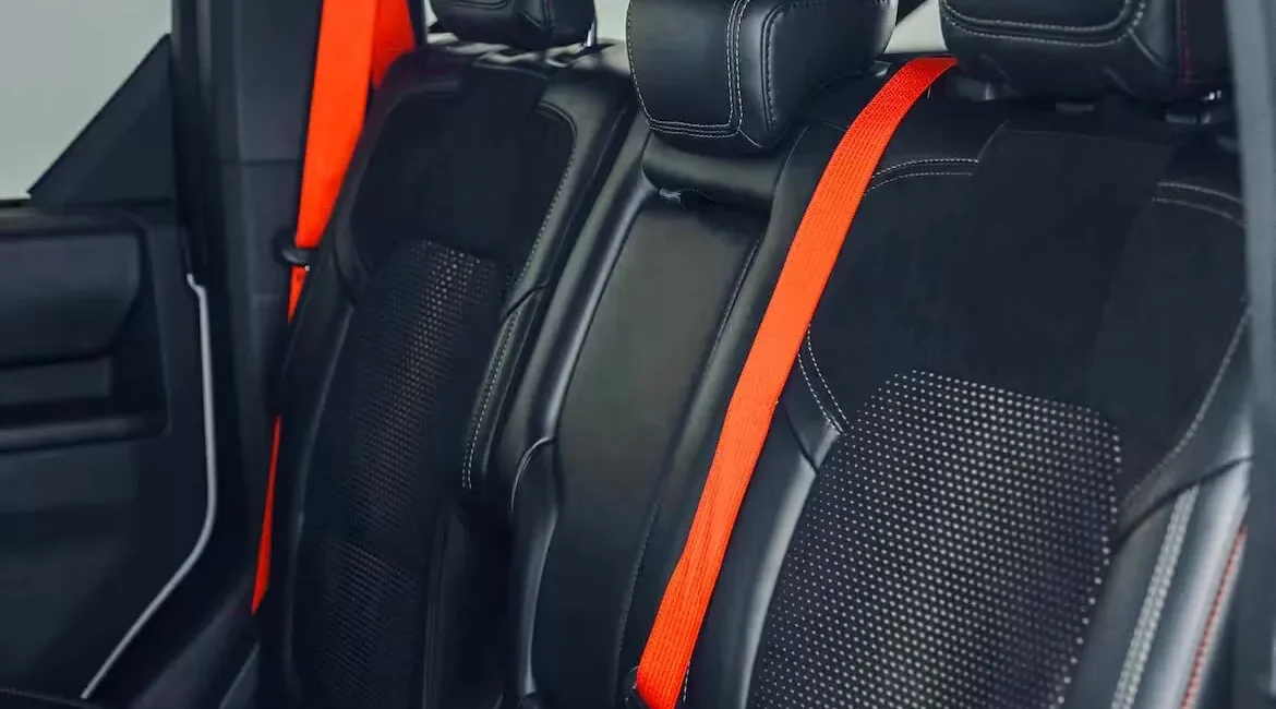 Black car seats with bright orange seat belts