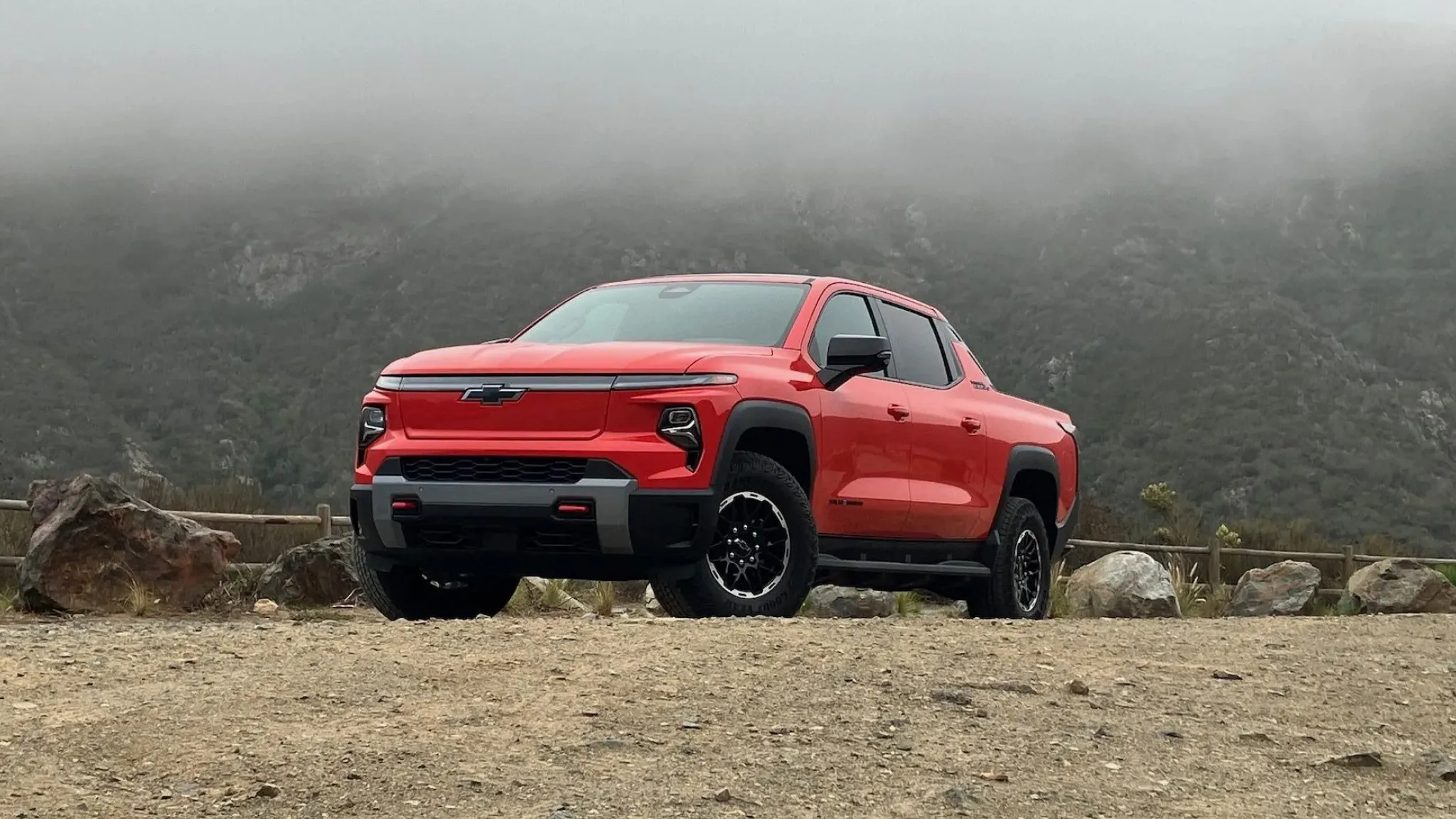 Red pickup truck parked in mountain fog.