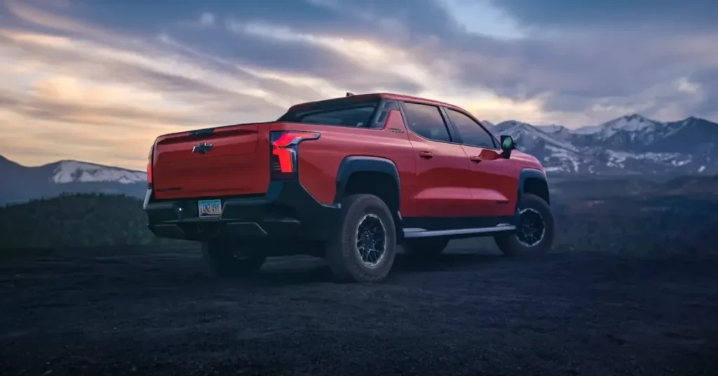 Red pickup truck parked near mountains at sunset