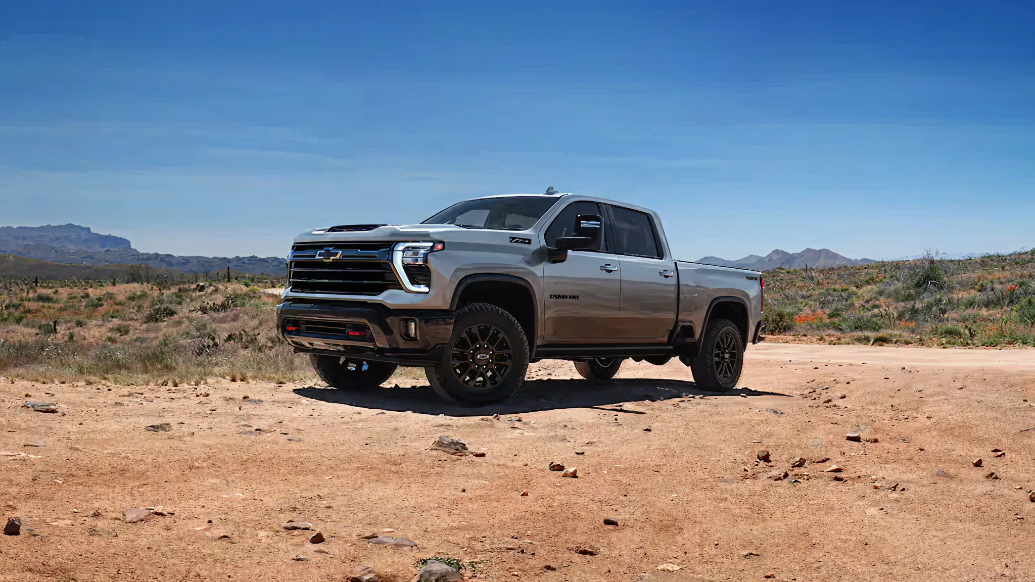 Silver pickup truck driving in desert terrain