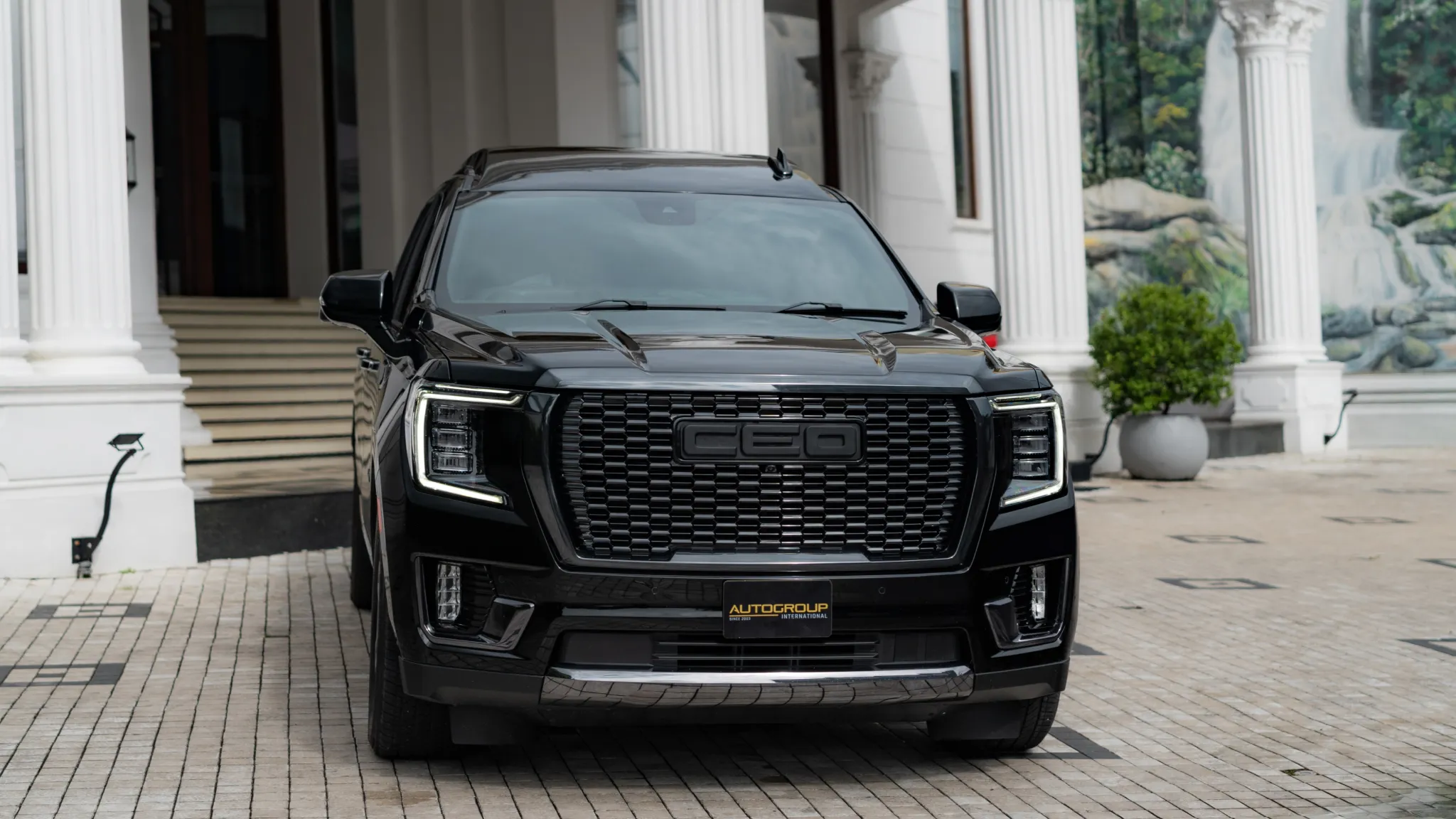 Black GMC SUV parked before luxury mansion