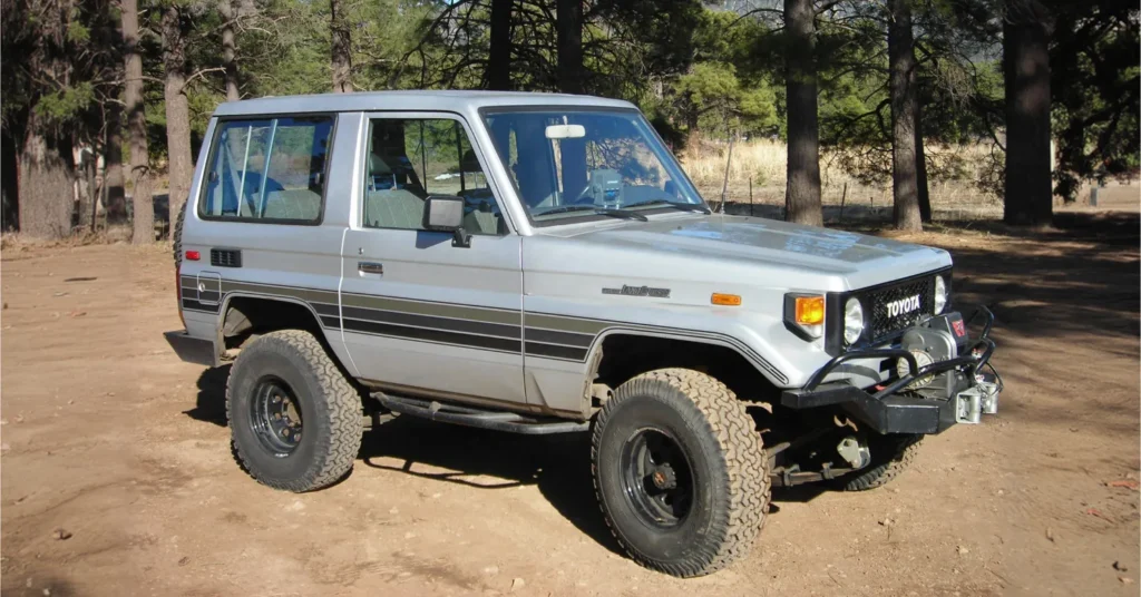 Vintage Toyota Land Cruiser parked in forest clearing