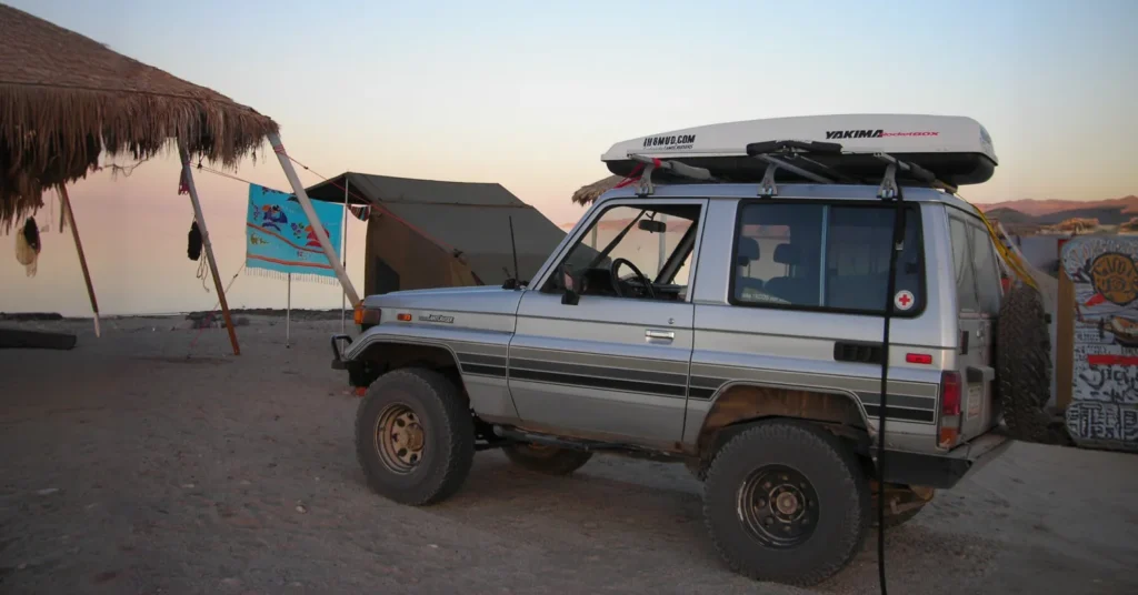 Off-road SUV parked at beach campsite sunset